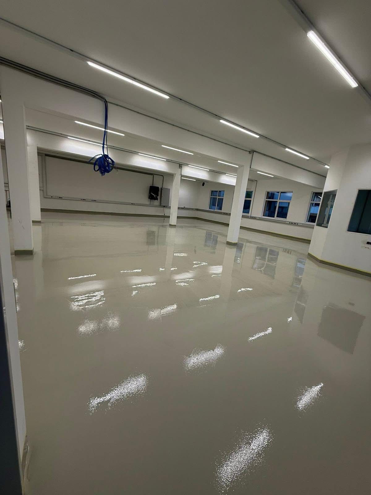 Cremefarbener Epoxidharzboden in heller Gewerbehalle mit fugenloser Hochglanz-Oberfläche