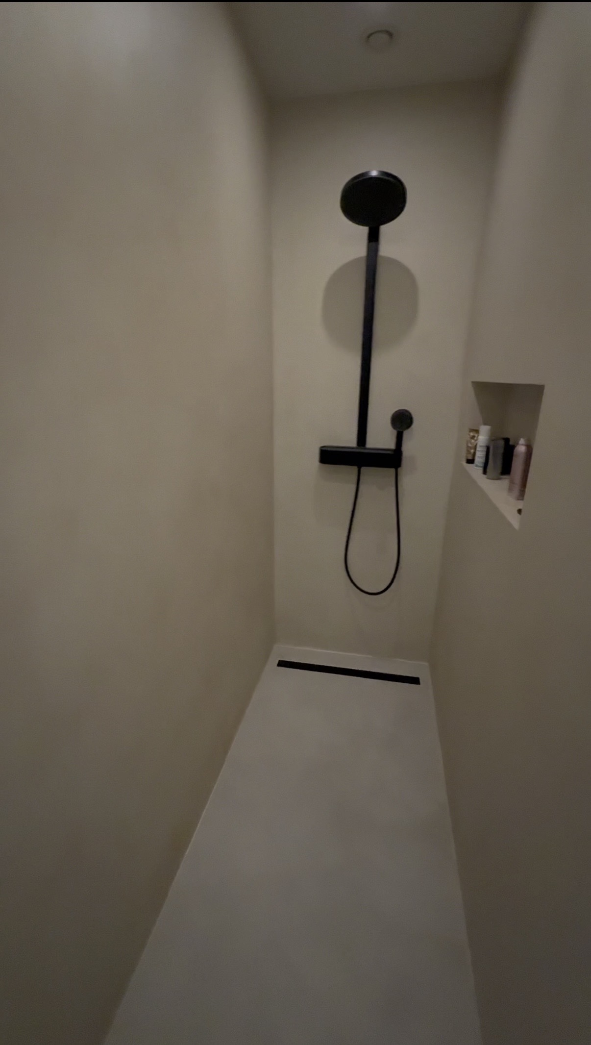 Begehbare Dusche fugenlos in Mikrozement Creme mit schwarzer Regenduscharmatur