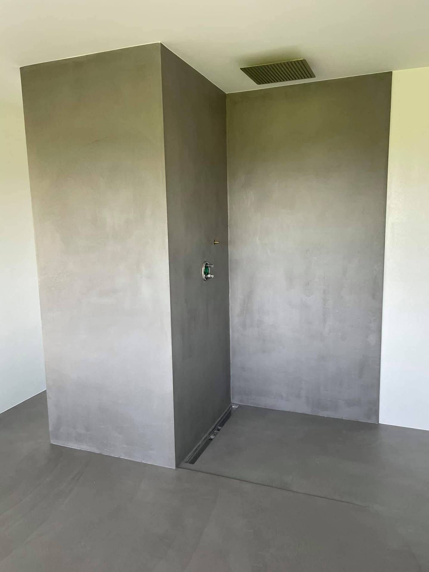 Fugenlose Dusche aus grauem Mikrozement, nahtloser Übergang von Wand zu Boden