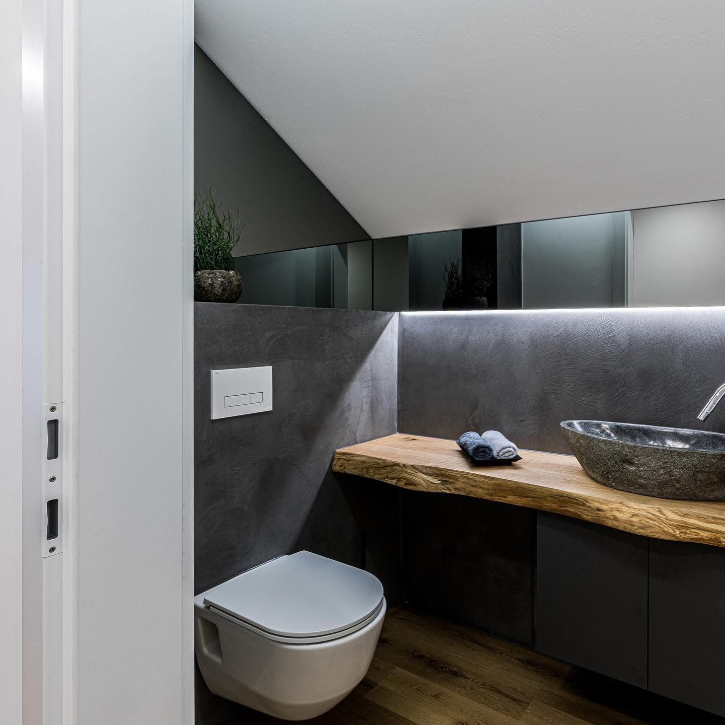 Gäste-WC mit Mikrozement Wand in Anthrazit, Holzwaschtisch und Steinwaschbecken