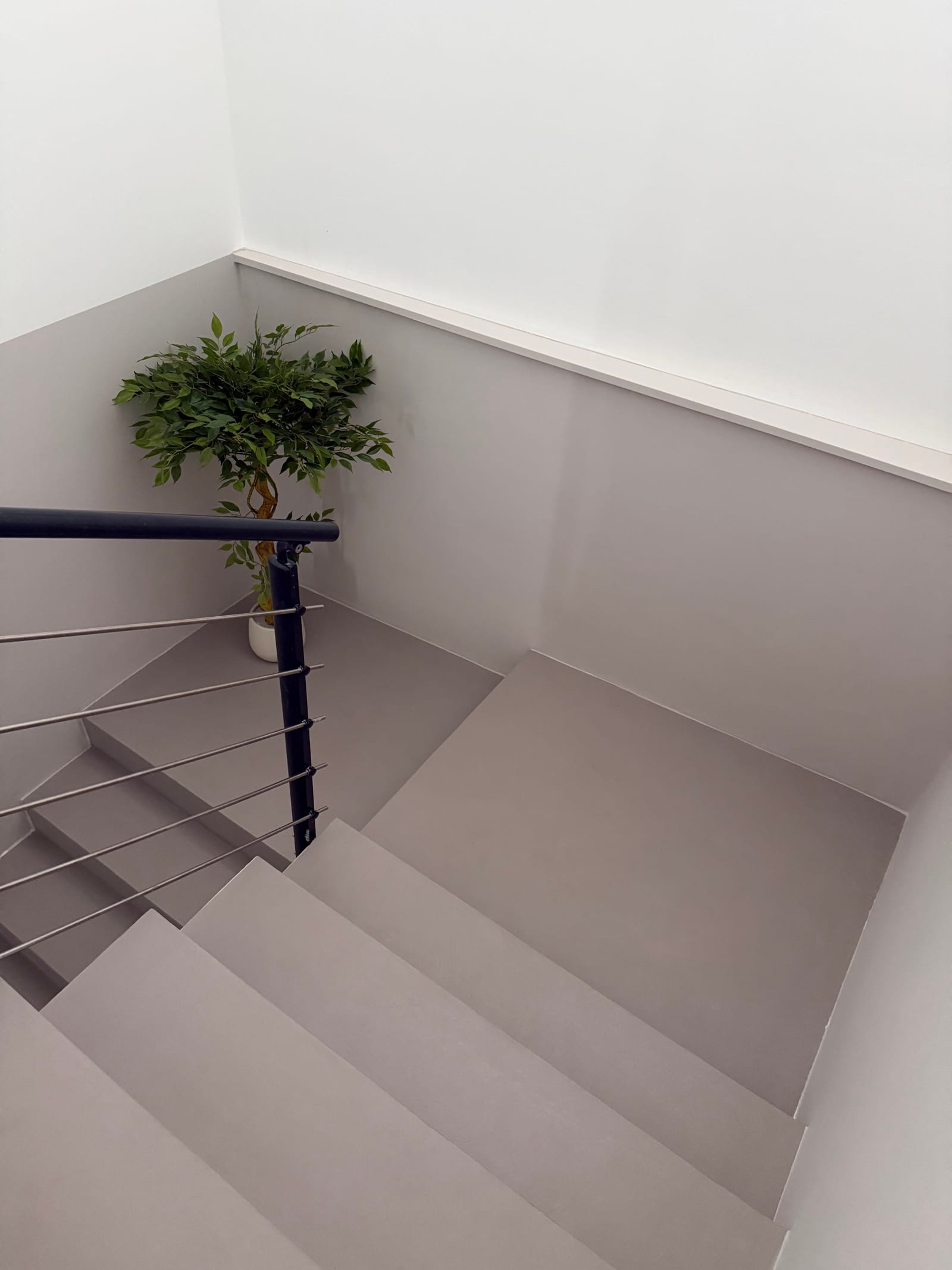 Fugenlose Mikrozement-Treppe in Grau mit Podest und umlaufender Wandbeschichtung, Blick von oben