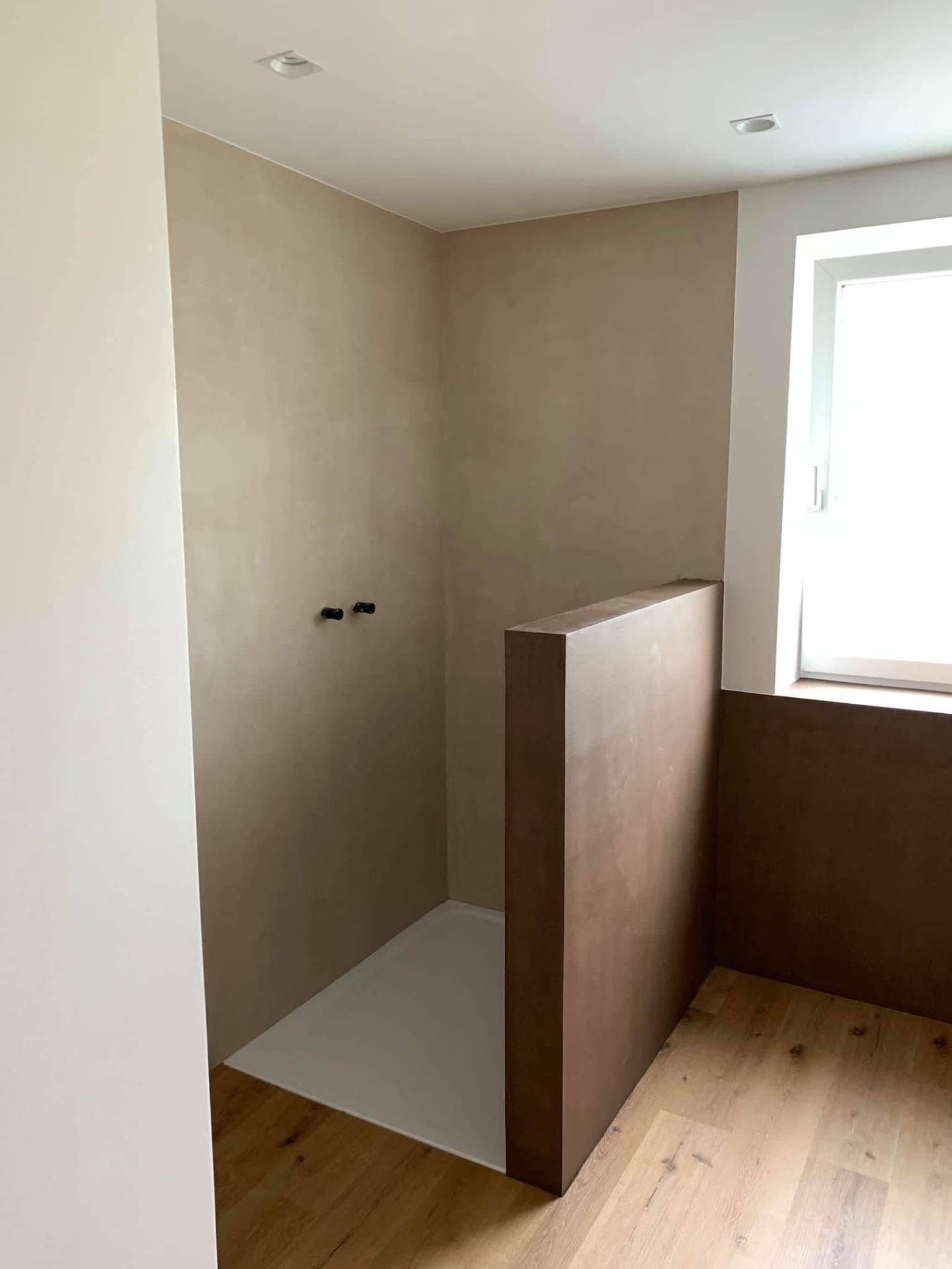 Walk-in-Dusche mit fugenlosem Mikrozement in Beige und Braun, kombiniert mit Holzboden