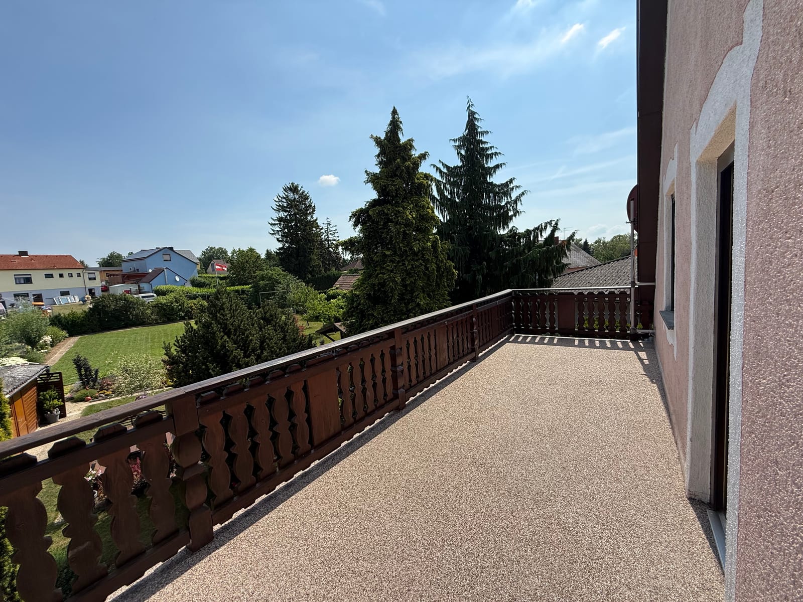 Natursteinteppich auf Balkon in Beige mit Holzgeländer und weitem Ausblick über die Gärten