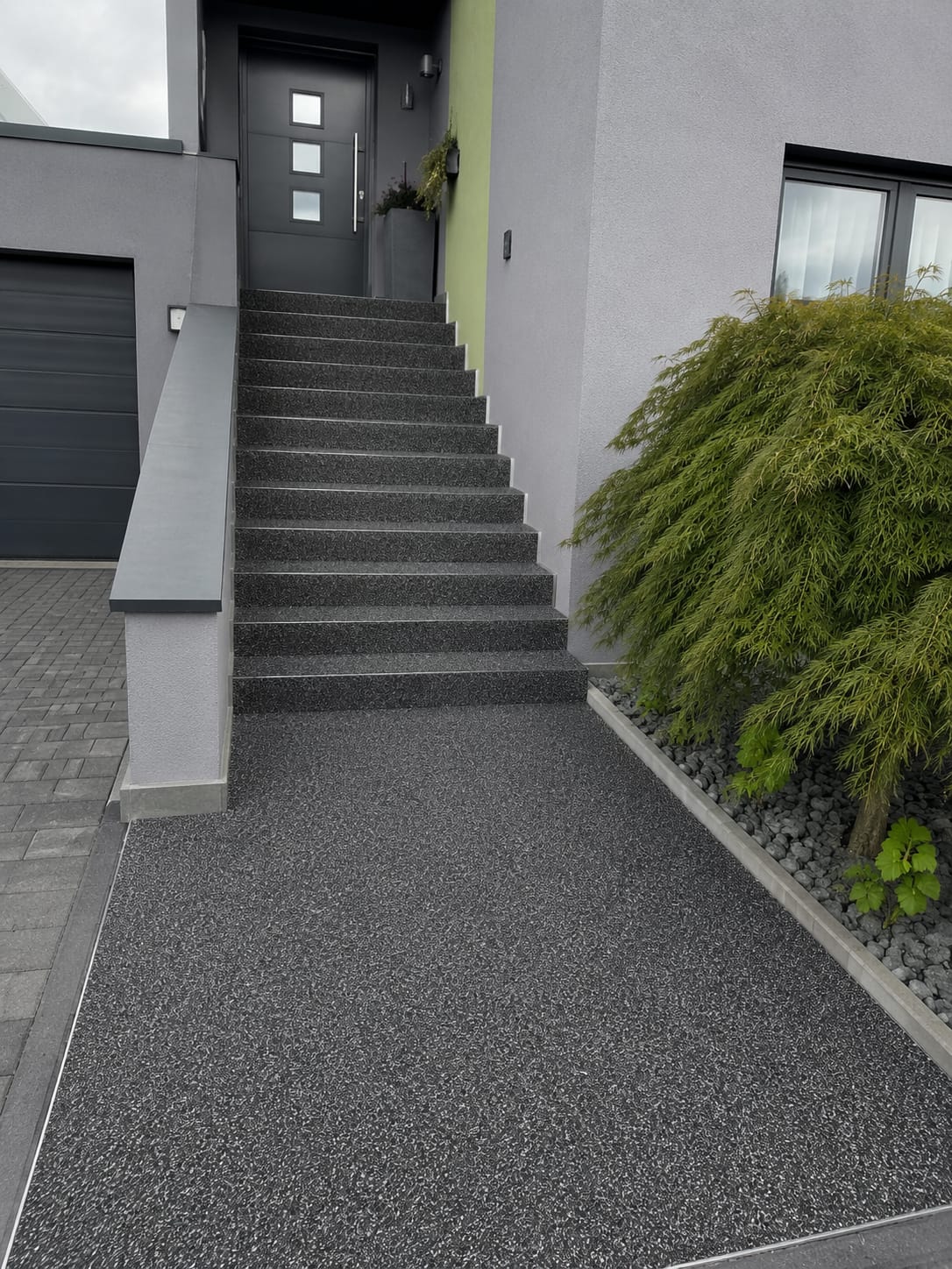 Hauseingang mit Natursteinteppich in Anthrazit, Treppe und Vorplatz an moderner Fassade