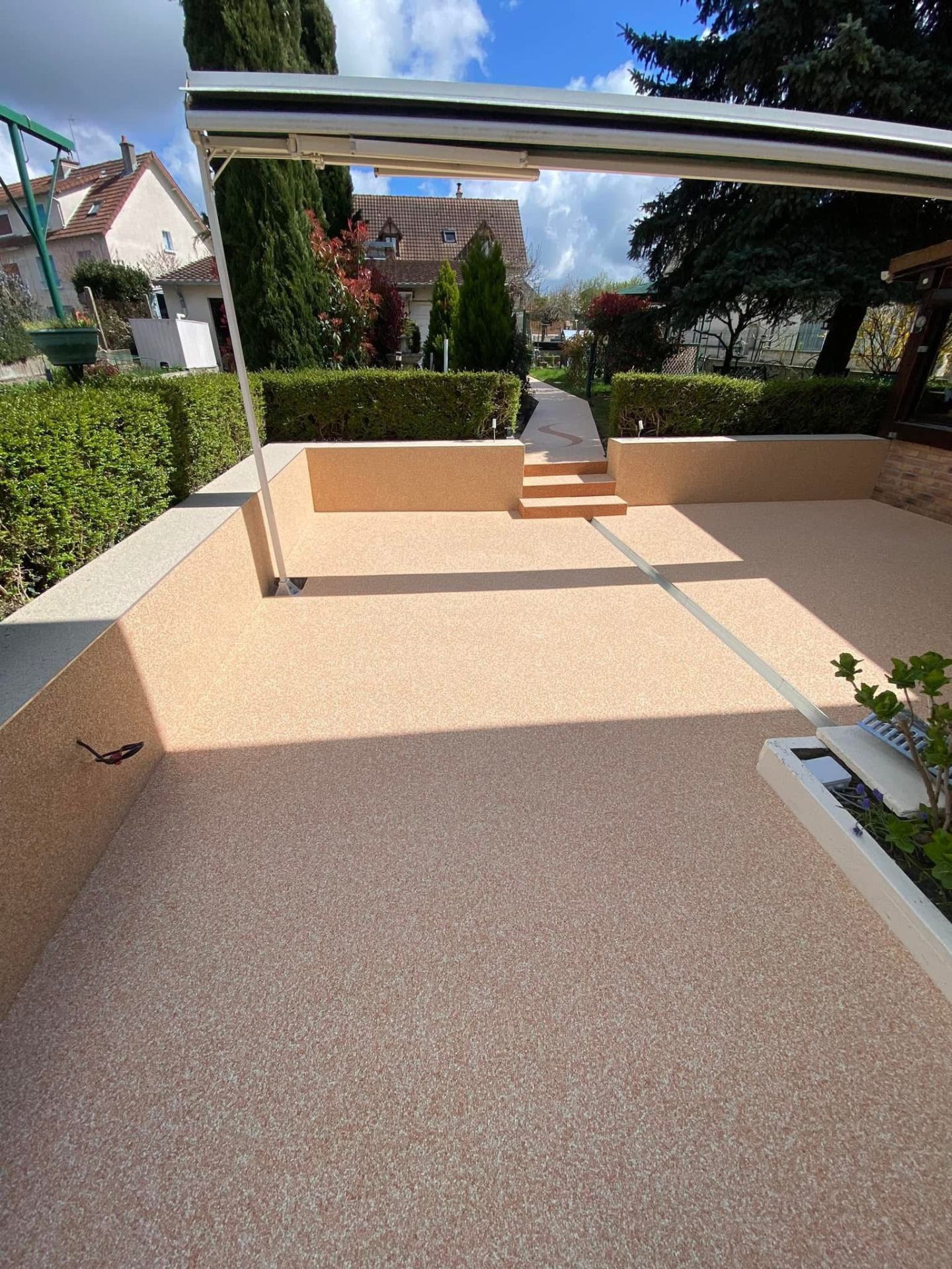 Natursteinteppich-Terrasse in Sand-Beige mit Marmorkies-Optik unter überdachter Pergola